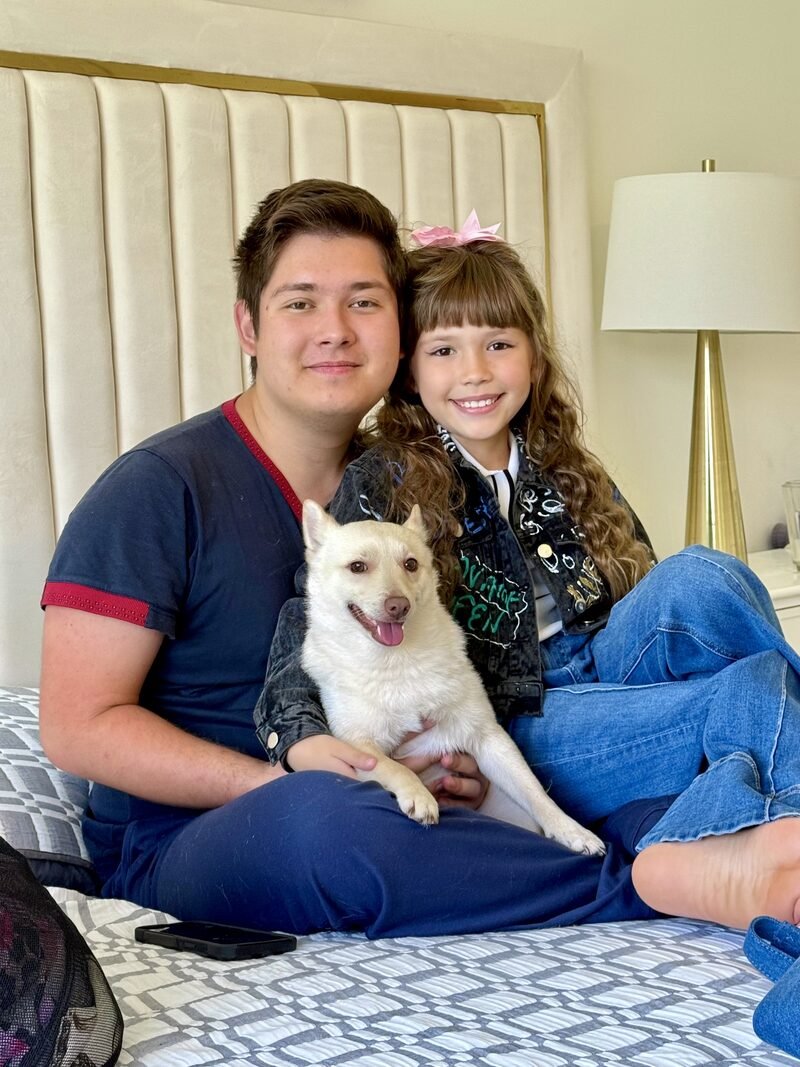 The brother and sister at home with one of their white Schipperke dogs